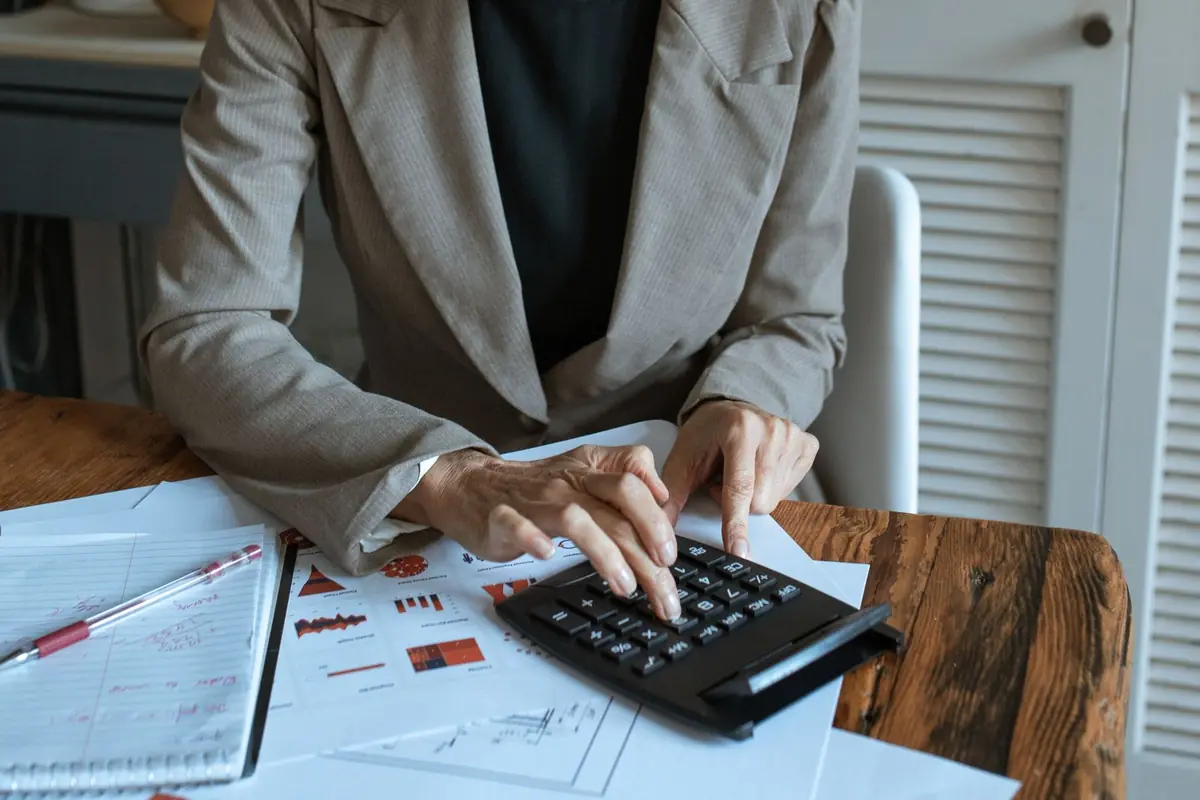 Small business owner working out what their business is worth using a calculator and financial reports